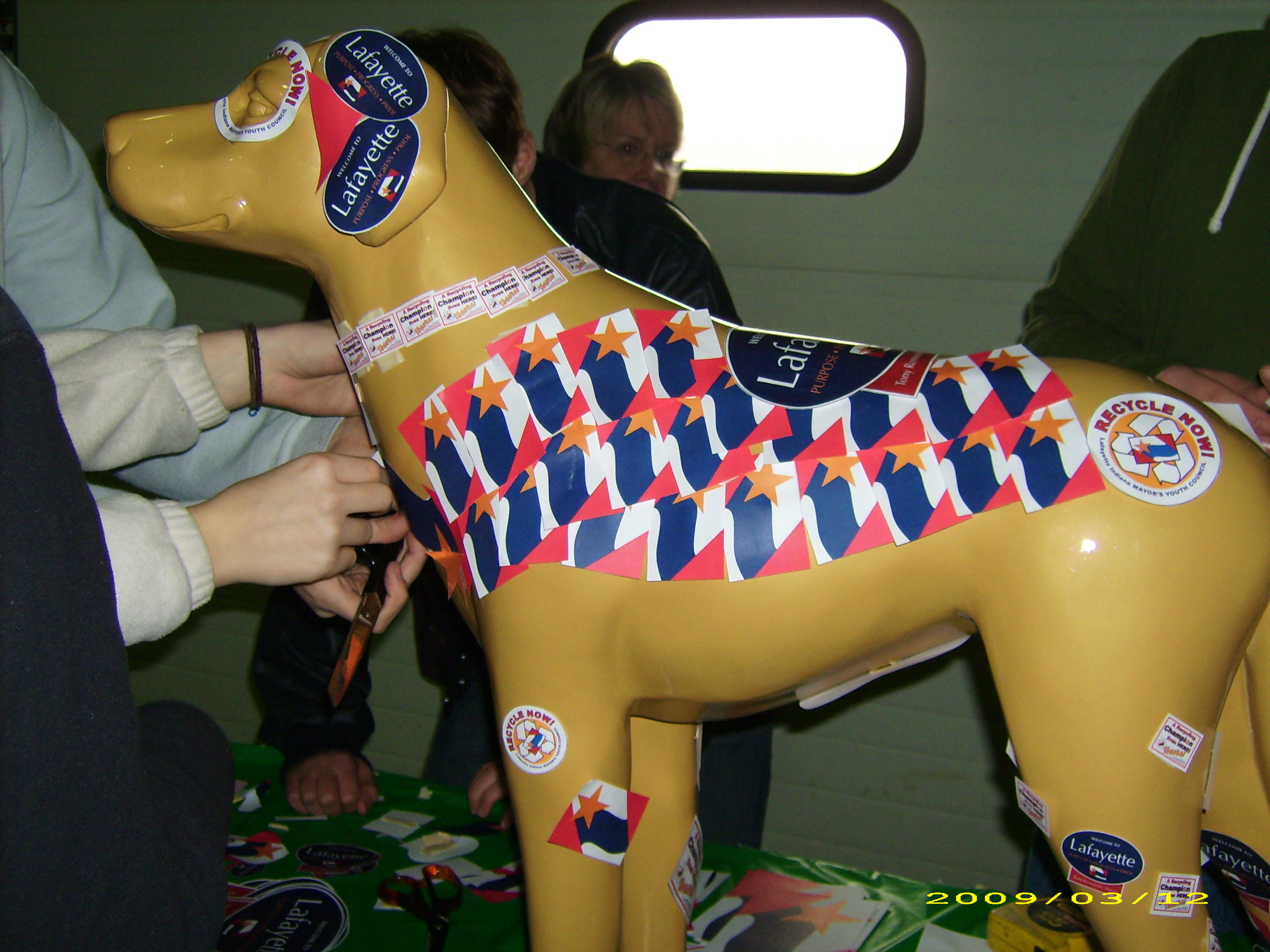 A plastic dog being decorated with city stickers